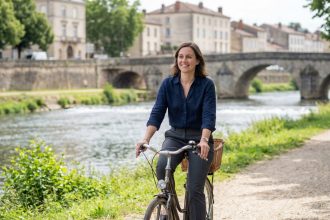Femme souriante en vélo dans Roanne avec ponts anciens